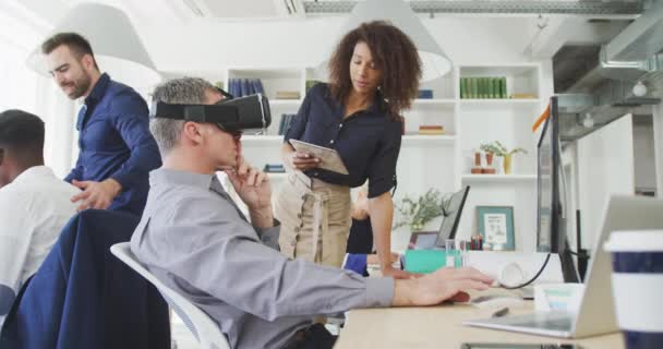 一个在现代办公室工作的白人商人头戴虚拟现实耳机 与他的女混血同事慢动作地交谈 触摸虚拟互动屏幕的侧视图 — 图库视频影像