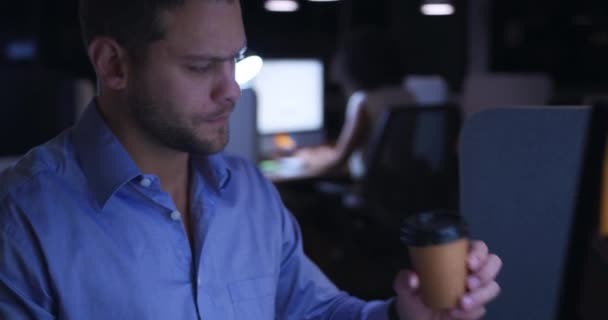 現代のオフィスで仕事をしている白人のビジネスマンの近くのサイドビュー コンピュータ画面を見て机に座って テイクアウトコーヒーを飲んで — ストック動画