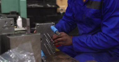 Bir fabrika atölyesinde çalışan, saç filesi takmış, metal parçaları hazırlayan ve kontrol eden Afro-Amerikan erkek işçilere yakından bakın.