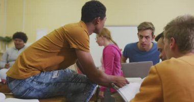 Sınıfta okuyan, etkileşim kuran ve birlikte çalışan, kitapları ve tablet bilgisayarı yavaş çekimde kullanan liseli genç erkek ve kız öğrencilerin yan görüntüsü.