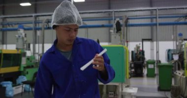 Yoğun bir fabrika deposunda çalışan, saç filesi takmış, plastik parçaları hazırlayan ve kontrol eden karışık ırk erkek işçilerinin yan görüntüsü.