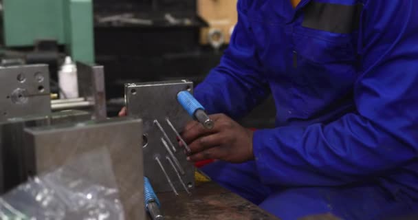 工場で働くアフリカ系アメリカ人男性の視点を閉じ ヘアネットと全体を着用し 金属部品の準備とチェック — ストック動画