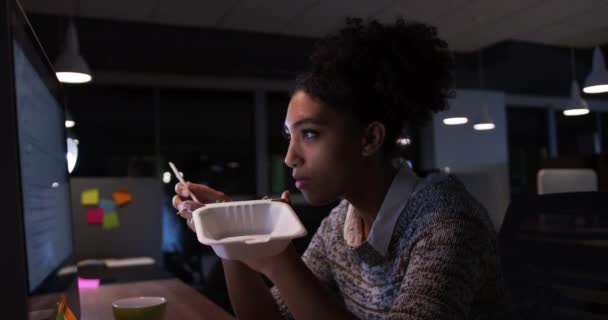 彼女の机の上に座ってコンピュータ画面を見てテイクアウトの食べ物を食べていました — ストック動画