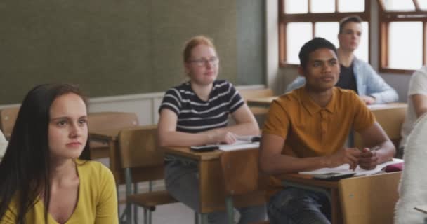 学校の教室に座って質問に答えるために手を挙げてゆっくりとした動きの中で — ストック動画