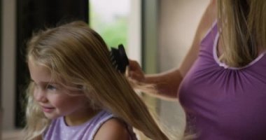 Kafkasyalı bir kadının yatak odasında boş zamanlarının tadını çıkarırken, genç kızının saçlarını yavaş çekimde tararken yan görüntüsü..