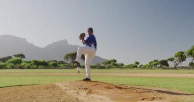 Beyzbol maçı sırasında, karışık ırktan bir erkek beyzbol oyuncusunun, güneşli bir günde, yavaş çekimde, top fırlatması ön planda.