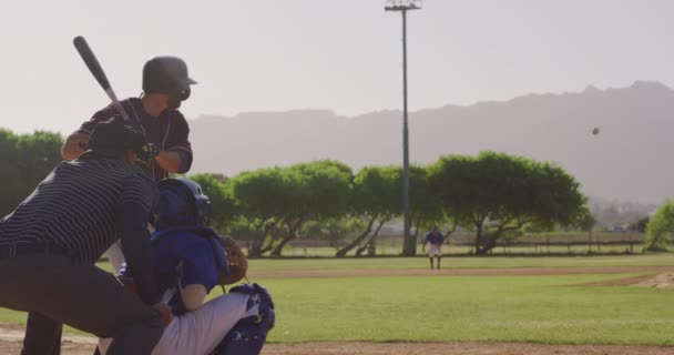 棒球比赛中白人男性棒球手的侧视图 用棒球棒击球 在阳光灿烂的日子里与前景光明的其他选手一起慢动作 — 图库视频影像