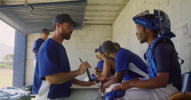 Entrenador Béisbol Masculino Caucásico Sosteniendo Portapapeles Instruyendo Jugador Béisbol Masculino — Vídeo de stock