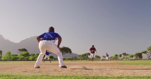 在阳光灿烂的日子里 一个白人男性棒球手在一场棒球赛中跑到基地 而一个非洲裔美国男性捕手在慢动作地接球 — 图库视频影像