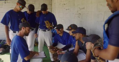 Kafkasyalı bir erkek beyzbol koçunun oyun planını açıklarken ve çok ırklı bir erkek beyzbol takımına maç öncesi hazırlık yaparken, soyunma odasında yavaşça otururken,