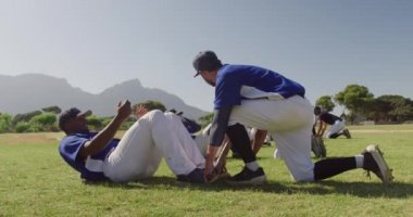 Kafkasyalı bir erkek beyzbol koçunun çok ırklı beysbol oyuncularına antrenman yaptırması, maçtan önce antrenman yapması, güneşli bir günde ağır çekimde antrenman yapması.