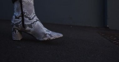 Bir yaz günü şehirde takılan ve deri kovboy çizmeleri giyen modaya uygun bir transseksüel ırk yetişkininin düşük kesiminden görüntüsü..