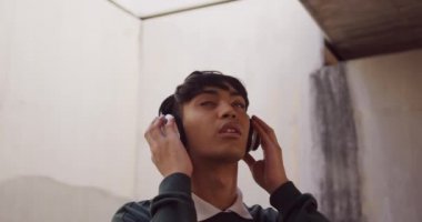 Önde, şehirde bir yaz günü takılan, kulaklık takan ve ağır çekimde müzik dinleyen modaya uygun bir transseksüel yetişkin var..