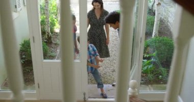 Kafkasyalı bir çiftin ve genç oğullarının evlerinin ön kapısından içeri girerken yüksek açılı görüntüsü, çocuklar merdivenlerden koşarken, ağır çekimde,