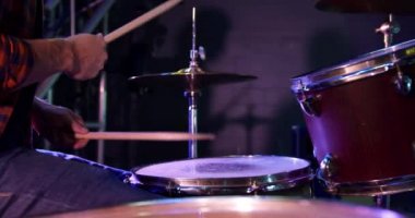 Yan görünüm, beyaz bir erkek davulcunun performanstan önce bir müzik mekanında prova yaparken, yavaş çekimde ve tutkuyla oturup davul çalarken.