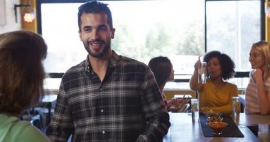 Kafkasyalı bir kadınla konuşan, bardaki karışık ırkçı bir adamın ön görüntüsü. Arkadaşları arka planda yavaş çekimde oturup tartışıyor.