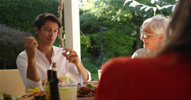 一位年长的白人妇女和她的成年儿子坐在外面的餐桌前 与家人共进晚餐 谈笑风生 动作缓慢 — 图库视频影像