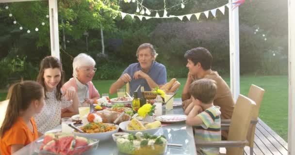 一个多代白人家庭坐在餐桌外吃饭 听祖父坐在餐桌前说话 慢吞吞地走来走去的高角形画面 — 图库视频影像