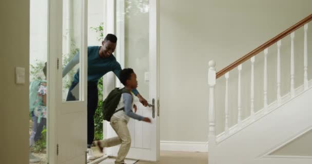新しい家の前のドアに入る若い息子と娘を持つアフリカ系アメリカ人のカップルの側面図は 子供たちがバックパックを着て階段を駆け上がる スローモーション — ストック動画