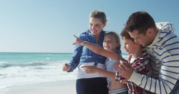 一緒にビーチで自由な時間を楽しんでいる彼らの息子と娘と一緒に白人のカップルの側の景色 スローモーションで背景に海と青い空で景色を賞賛することを受け入れます — ストック動画