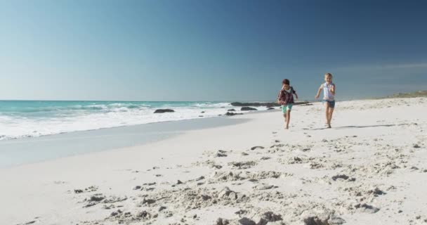 一个快乐的白人男孩和女孩一起享受沙滩上的闲暇时光 光着脚在沙滩上奔跑 背景是大海和蓝天 动作缓慢 — 图库视频影像