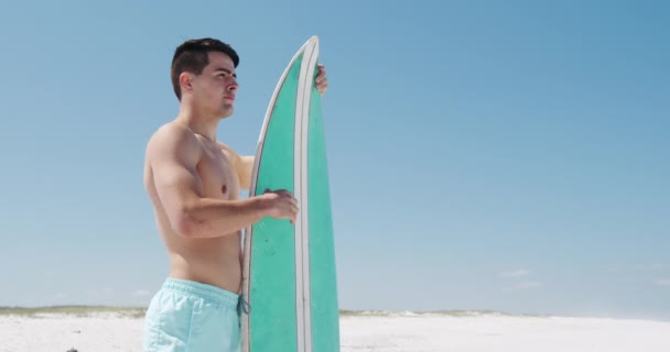 해변가에서 시간을 즐기고 남자의 각도의 배경에 모래와 경치를 파도타기 움직임으로 — 비디오