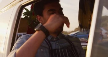 Yemek kamyonunda oturan yorgun, kafası ağır çekimde dinlenen melez bir adamın ön görüntüsü.