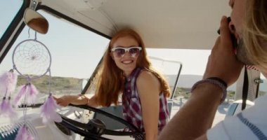 Kafkas 'lı genç bir adam ve kadının güneşli bir sahilde karavanda fotoğraf çekerken görüntüsü.