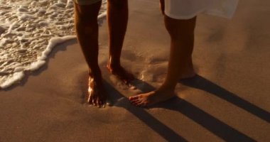 Deniz kenarında güneşli bir sahilde boş vakitlerin tadını çıkaran genç bir melez çiftin alçak kesimi.