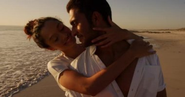 Deniz kenarında güneşli bir kumsalda boş vakit geçiren genç bir melez çiftin ön görüntüsü.