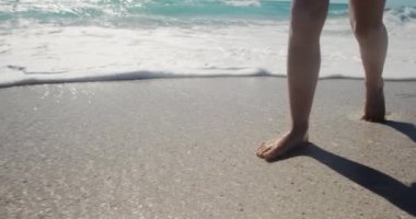 Kafkasyalı bir kızın güneşli bir kumsalda çıplak ayakla yürüdüğünü ve dalgaların yavaş çekimde ayaklarına doğru geldiğini gördüm.