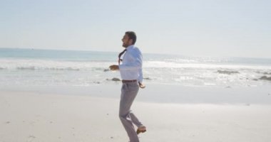 Genç bir melez işadamının önünde dans ederek ve deniz kenarında ayakkabılarını çıkararak boş zaman geçirmesinin keyfini çıkarırken.