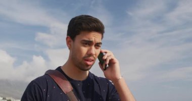 Güneşli bir günde doğada boş vakit geçiren, akıllı bir telefonla konuşan, saatini yavaş çekimde kontrol eden melez bir ırkın ön görüntüsü.