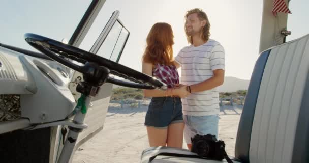 在海边阳光明媚的海滩上 一个年轻的白人男人和女人享受着与野营车拥抱的闲暇时光 — 图库视频影像