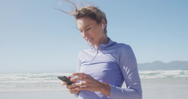 在阳光明媚的日子里 一个高加索女人在海边享受着闲暇时光 她用智能手机慢动作 — 图库视频影像