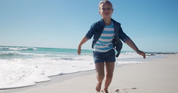 青い空とゆっくりとした動きの背景に海と 実行されている晴れたビーチで白人の女の子のフロントビュー — ストック動画