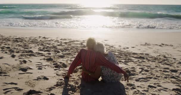 Visão Traseira Casal Caucasiano Sênior Praia Sol Abraçando Sentado Frente — Vídeo de Stock