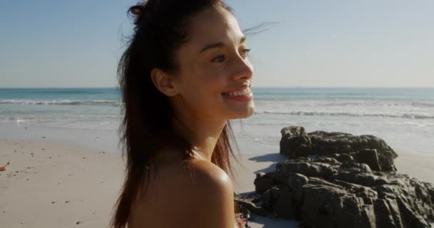 海のそばの日当たりの良いビーチで自由な時間を楽しんでいる若い混合レースの女性の肖像画 カメラに笑顔 — ストック動画