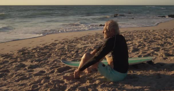 해변에서 일광욕을 파도타기판 동작으로 바다를 바라보고 코카서스 노인의 — 비디오
