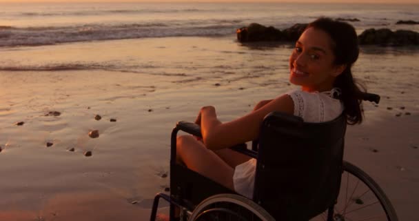 Tekerlekli Sandalyedeki Genç Bir Kadının Portresi Gün Batımında Sahilde Kameraya — Stok video