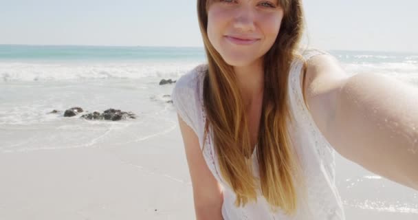 一个年轻的白人女人的画像 她在海边一个阳光明媚的海滩上享受着闲暇时光 对着相机微笑 — 图库视频影像