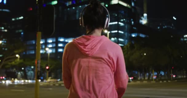 머리에 운동복을 밤에는 밖에서 운동을 헤드폰을 따뜻하게 달리기 시작하는 여성의 — 비디오