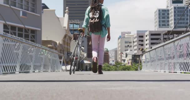 在一个阳光灿烂的日子里 一个身披背包 走在大街上 慢吞吞地骑着自行车 满城风雨的混血男子的后视镜 — 图库视频影像