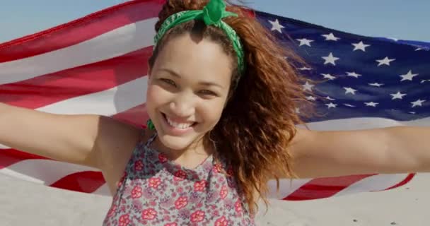 一位年轻的白人妇女在海边阳光灿烂的海滩上享受着高举美国国旗的闲暇时光 — 图库视频影像