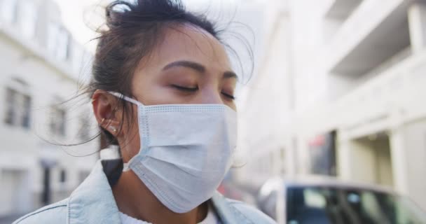 大気汚染やコロナウイルスに対して顔マスクを着用し スローモーションの背景に建物で咳をし 日中と街の通りに長い暗い髪を持つ病気の混合レースの女性の側面図 — ストック動画