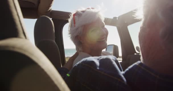 道路の旅行中に車の中で座っているシニア白人のカップルの肩のビューの近くに 太陽の下でビーチに運転し ホイールで男は スローモーションでお互いを見て — ストック動画