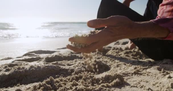 해변에서 일광욕을 즐기며 앉아서 천천히 모래에 코카서스 노인의 가까이 — 비디오