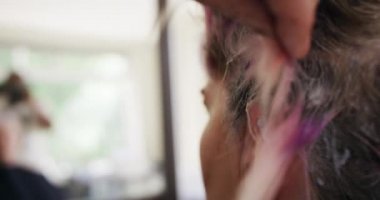 Alternatif havalı kuaför salonu. Kafkas erkek bir kuaförün arka görüntüsü. Kuaförde çalışıyor, elinde fırça, beyaz kadın bir müşterinin saçlarını yavaş çekimde boyuyor.