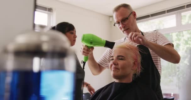 替代凉爽发廊 在美发厅工作的白人男性理发师 拿着吹风机 慢动作的白人女性吹干头发的侧视图 — 图库视频影像
