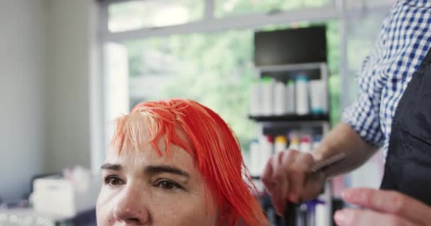 代替クールなヘアサロン ヘアサロンで働く白人男性の美容師の正面図 白人女性のクライアントの赤い髪を結合し 撫でる スローモーションで — ストック動画